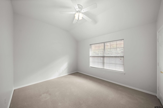 carpeted spare room featuring ceiling fan and vaulted ceiling