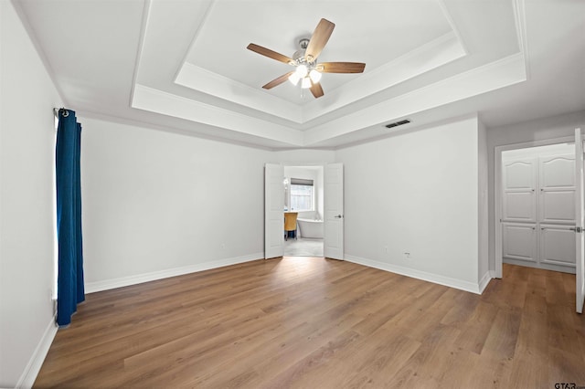 empty room featuring light hardwood / wood-style flooring, a raised ceiling, and ceiling fan