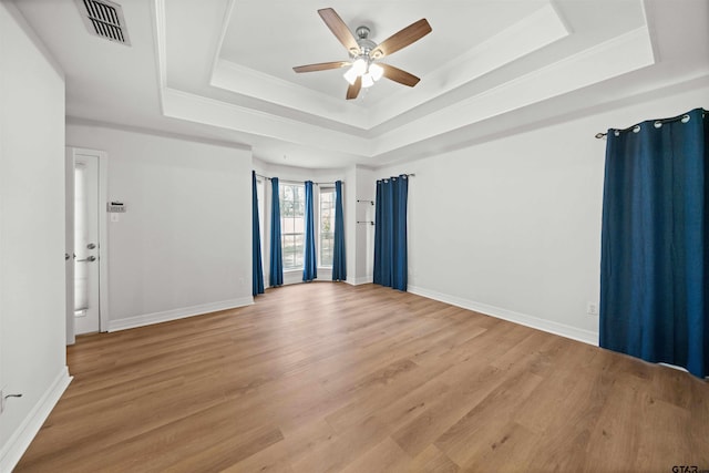 empty room with a raised ceiling, ceiling fan, and hardwood / wood-style floors