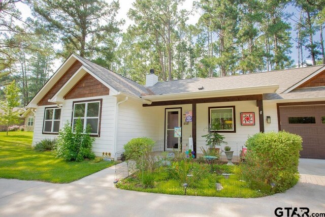 711 N Green Meadow Trl, Holly Lake Ranch, TX 75765 - ranch-style house featuring a garage, a chimney, a front lawn, covered porch, and a shingled roof