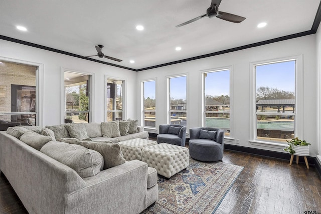 living room featuring dark wood-type flooring, ceiling fan, ornamental molding, and a wealth of natural light