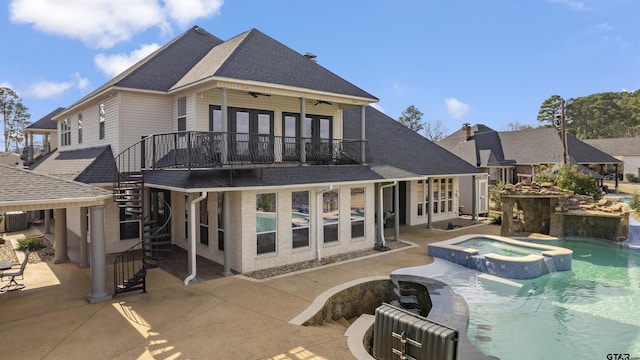 back of property featuring a balcony, a swimming pool with hot tub, ceiling fan, central air condition unit, and a patio area