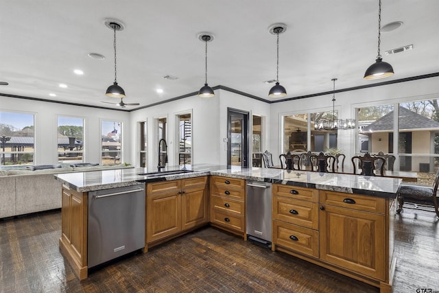 kitchen featuring light stone counters, stainless steel dishwasher, sink, and hanging light fixtures