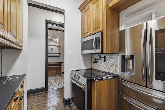 kitchen featuring tasteful backsplash, appliances with stainless steel finishes, dark wood-type flooring, and dark stone counters