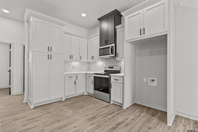 kitchen with light hardwood / wood-style floors, white cabinetry, appliances with stainless steel finishes, and tasteful backsplash