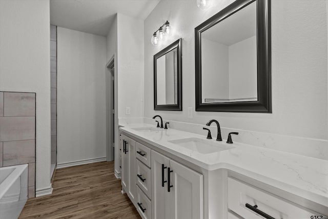 bathroom with a washtub, vanity, and wood-type flooring