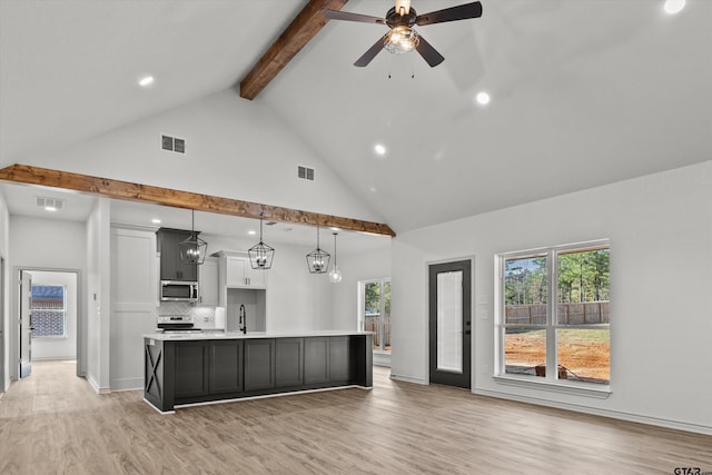 kitchen with stainless steel appliances, high vaulted ceiling, a spacious island, decorative light fixtures, and light hardwood / wood-style floors