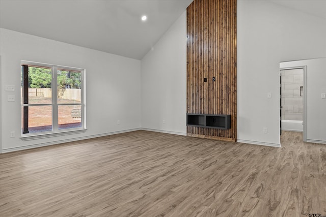 unfurnished living room featuring light wood-type flooring, a fireplace, and high vaulted ceiling