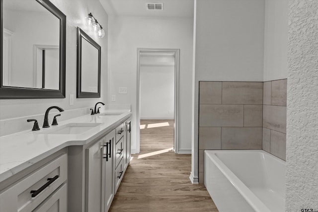 bathroom with vanity, wood-type flooring, and a tub to relax in