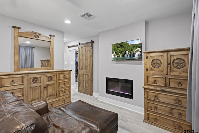 interior space with recessed lighting, baseboards, a glass covered fireplace, visible vents, and wood finished floors