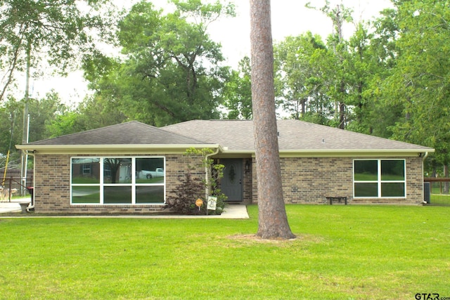 view of front facade featuring a front yard, brick siding, and a shingled roof
