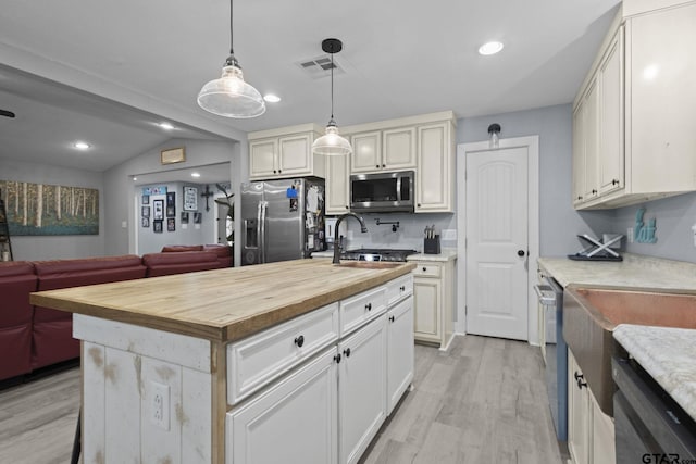 kitchen featuring light wood finished floors, wooden counters, stainless steel appliances, open floor plan, and visible vents