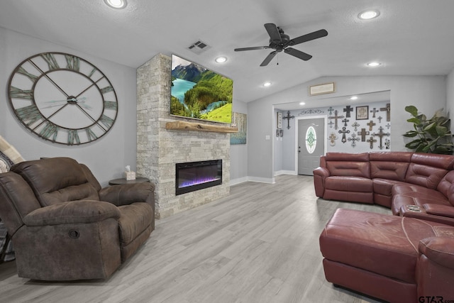 living room featuring vaulted ceiling, ceiling fan, visible vents, wood finished floors, and a fireplace