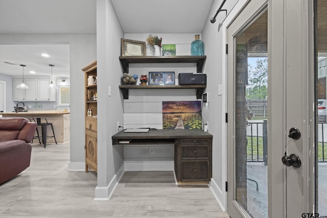 interior space featuring a sink, pendant lighting, baseboards, light wood-style floors, and recessed lighting
