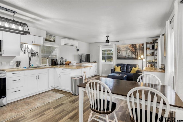 kitchen with light hardwood / wood-style flooring, hanging light fixtures, a wall unit AC, and white cabinets