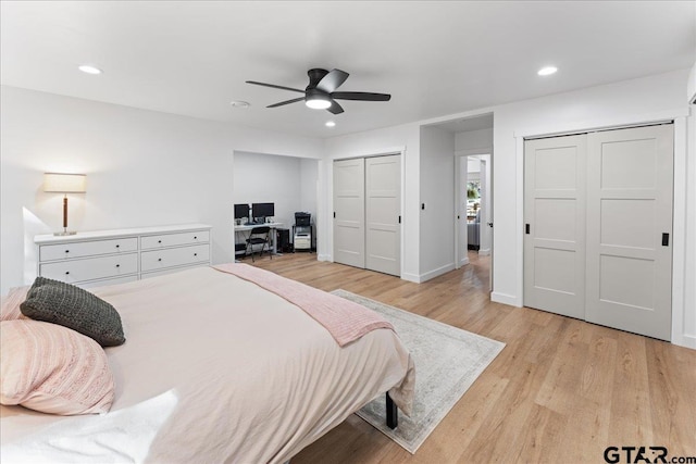 bedroom featuring ceiling fan, multiple closets, and light hardwood / wood-style flooring