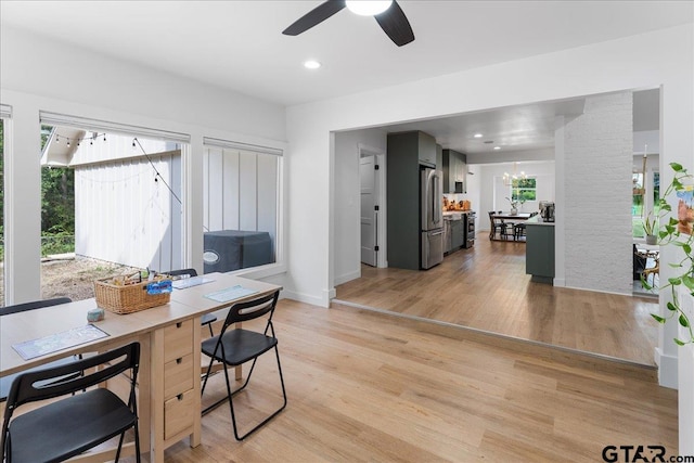 home office with light hardwood / wood-style floors and ceiling fan with notable chandelier