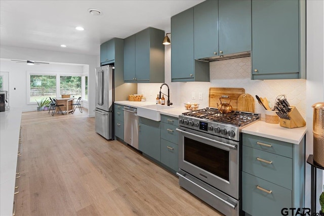 kitchen featuring backsplash, sink, light wood-type flooring, blue cabinetry, and high quality appliances