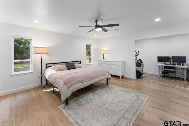 bedroom featuring ceiling fan, light hardwood / wood-style floors, and multiple windows