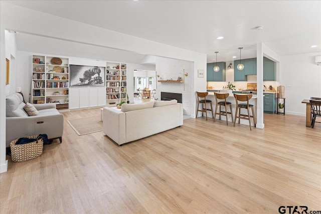 living room featuring built in shelves, a large fireplace, and light hardwood / wood-style flooring