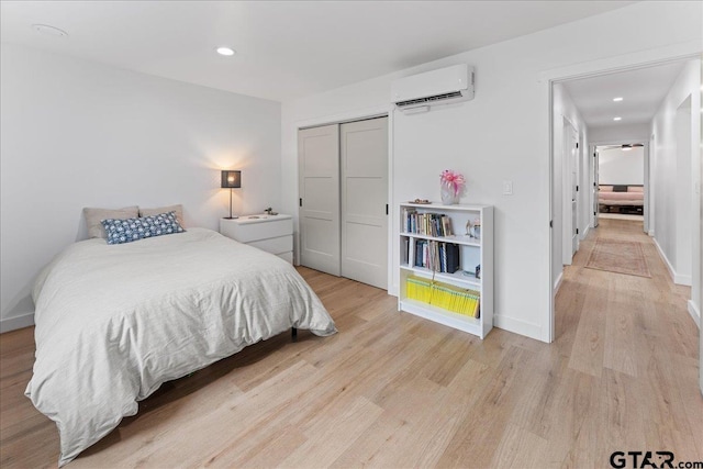 bedroom with a closet, light hardwood / wood-style flooring, and an AC wall unit