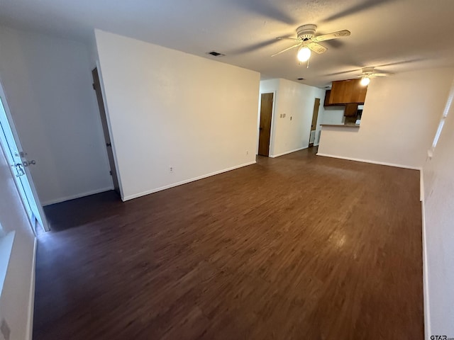 unfurnished living room featuring dark wood-type flooring and ceiling fan