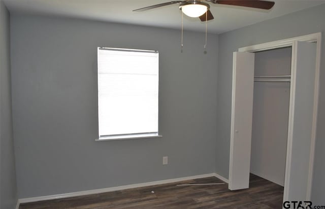 unfurnished bedroom with multiple windows, ceiling fan, a closet, and dark wood-type flooring