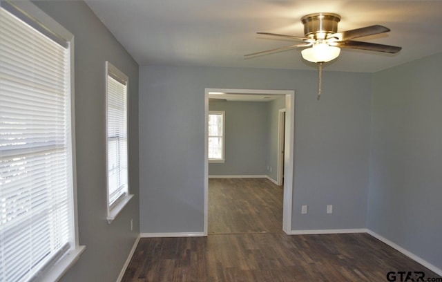 empty room featuring a healthy amount of sunlight, ceiling fan, and dark wood-type flooring