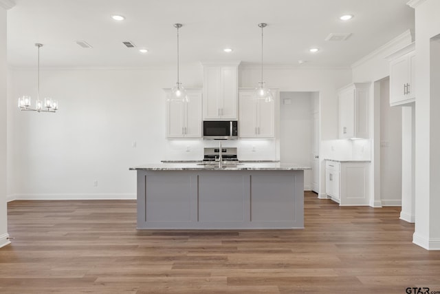 kitchen with white cabinets, light hardwood / wood-style flooring, and hanging light fixtures