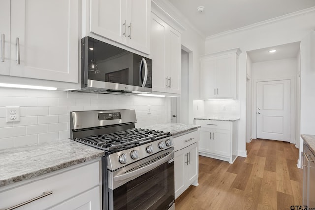 kitchen featuring white cabinetry, light stone countertops, tasteful backsplash, light hardwood / wood-style floors, and appliances with stainless steel finishes