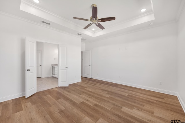 unfurnished bedroom featuring a raised ceiling, ceiling fan, crown molding, and light wood-type flooring