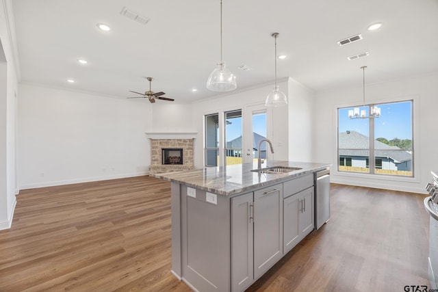 kitchen featuring gray cabinetry, a healthy amount of sunlight, a center island with sink, and light wood-type flooring