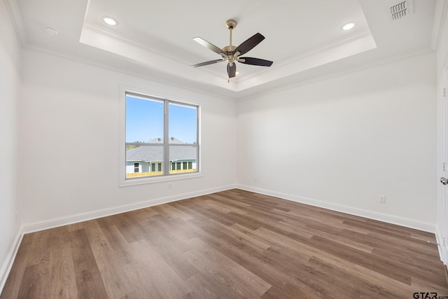 empty room with hardwood / wood-style floors, a tray ceiling, ceiling fan, and crown molding