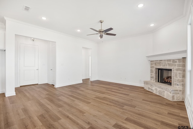 unfurnished living room with a stone fireplace, light wood-type flooring, and crown molding