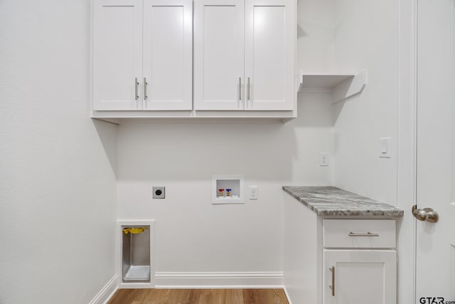 laundry area with hookup for an electric dryer, washer hookup, light hardwood / wood-style floors, and cabinets