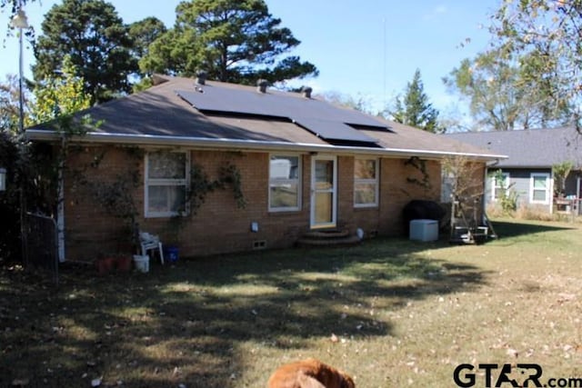 back of property featuring a lawn and solar panels