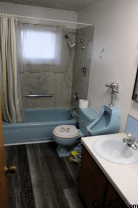 307 Lowry St, Arp, TX 75750 - bathroom featuring shower / bathtub combination with curtain, toilet, vanity, and wood finished floors