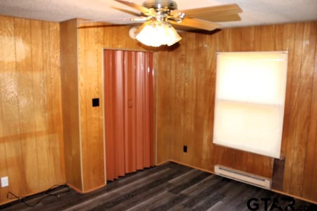 empty room with baseboard heating and wood walls