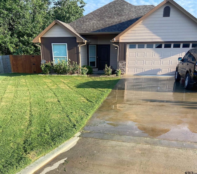 ranch-style home featuring an attached garage, fence, driveway, roof with shingles, and a front yard