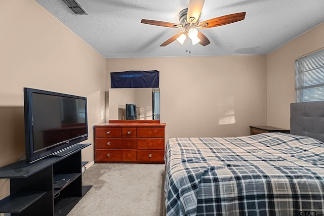 bedroom with visible vents, ceiling fan, light carpet, and a textured ceiling