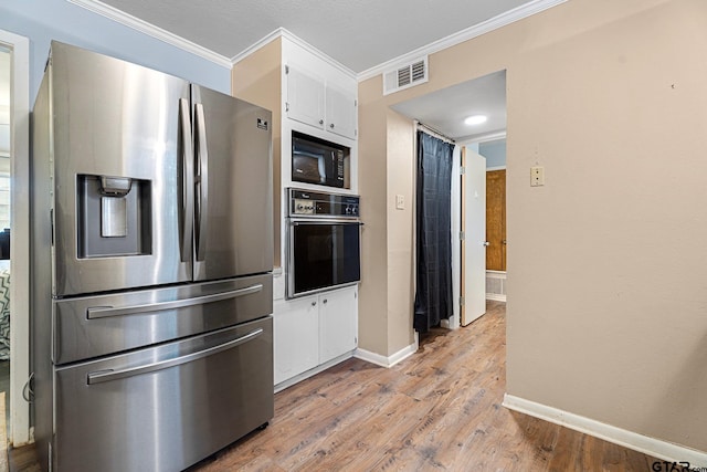 kitchen featuring stainless steel refrigerator with ice dispenser, wall oven, ornamental molding, white cabinets, and black microwave