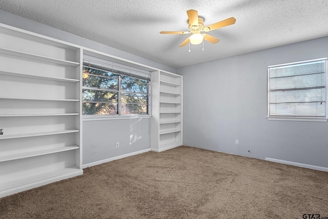 unfurnished bedroom with carpet floors, ceiling fan, baseboards, and a textured ceiling