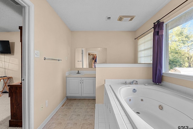 bathroom featuring visible vents, vanity, a whirlpool tub, and a textured ceiling