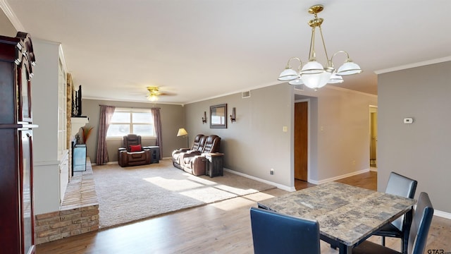 interior space featuring visible vents, light wood-style flooring, ornamental molding, baseboards, and ceiling fan with notable chandelier