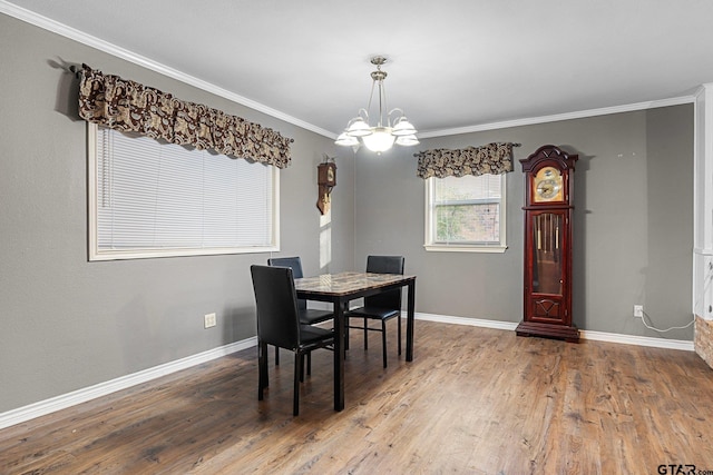 dining area with baseboards, ornamental molding, wood finished floors, and an inviting chandelier