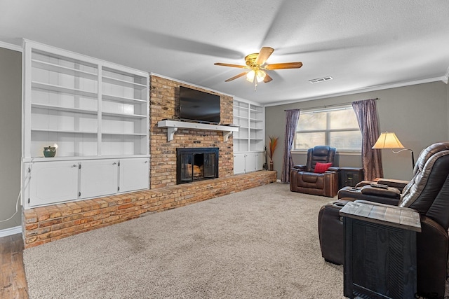 carpeted living room featuring a textured ceiling, ceiling fan, ornamental molding, and a fireplace