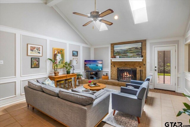 17599 Autumn Trl, Whitehouse, TX 75791 - tiled living room featuring a fireplace, lofted ceiling with skylight, ceiling fan, and a decorative wall