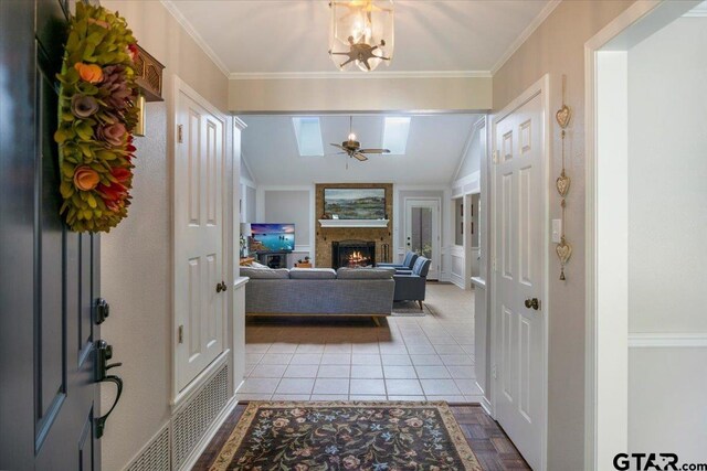 17599 Autumn Trl, Whitehouse, TX 75791 - entryway with ceiling fan with notable chandelier, a warm lit fireplace, ornamental molding, and light tile patterned flooring