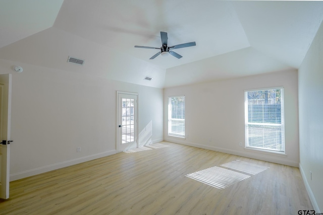 spare room featuring lofted ceiling, light hardwood / wood-style flooring, ceiling fan, and a healthy amount of sunlight