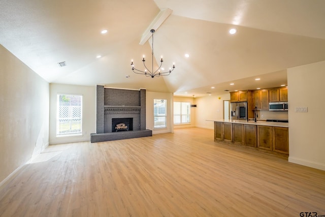 unfurnished living room featuring a wealth of natural light, light hardwood / wood-style flooring, and a brick fireplace